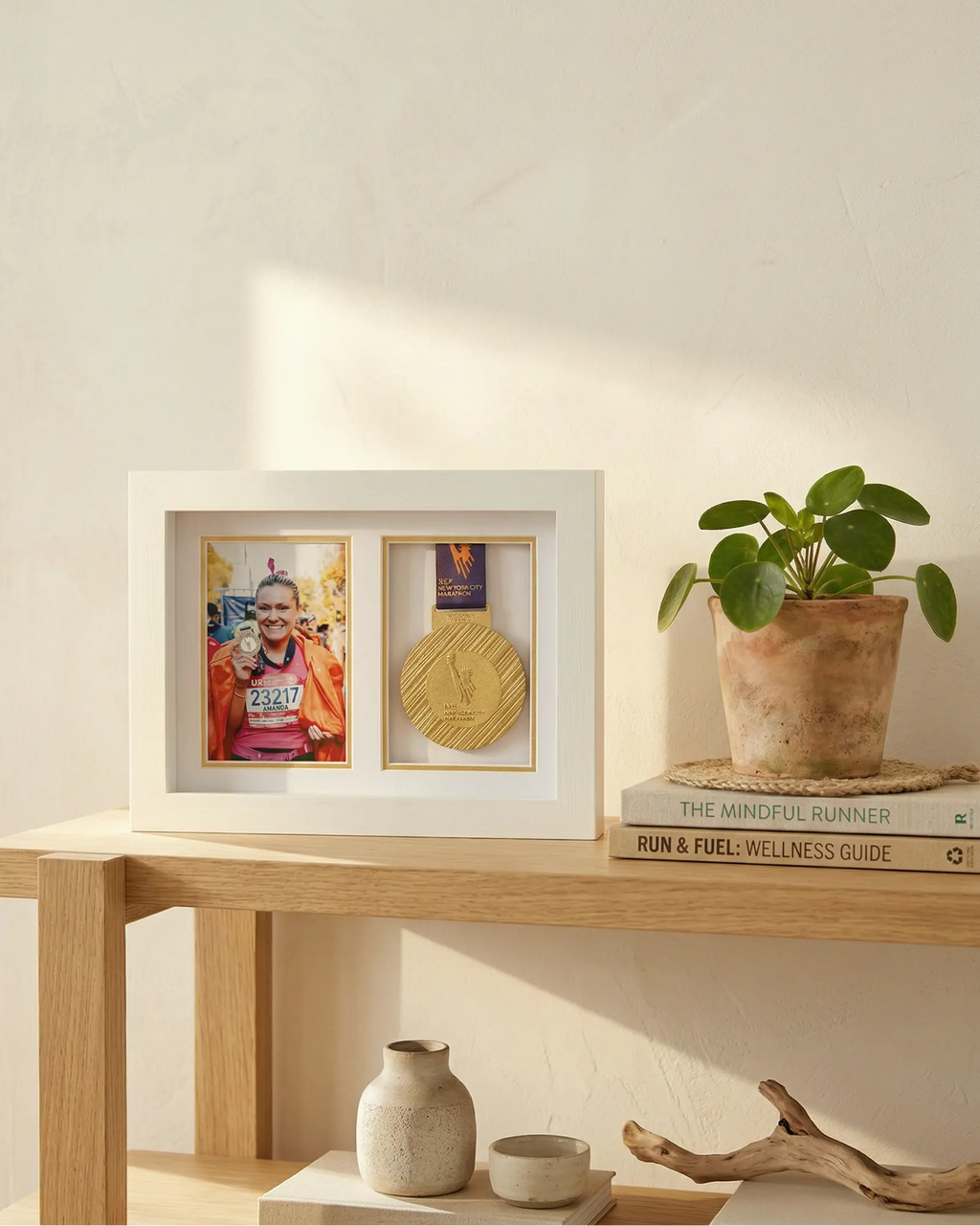 Framed photo of a person with anew york marathon medal on a wooden shelf with a plant and books.